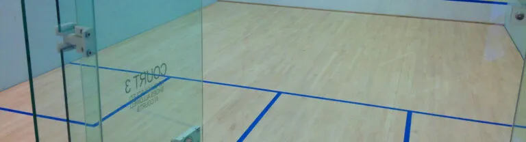 Glass-back squash court with a maple floor and blue court lines