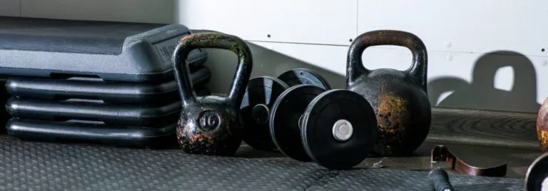 Kettlebells, dumbbells and step platforms on a rubber gym floor