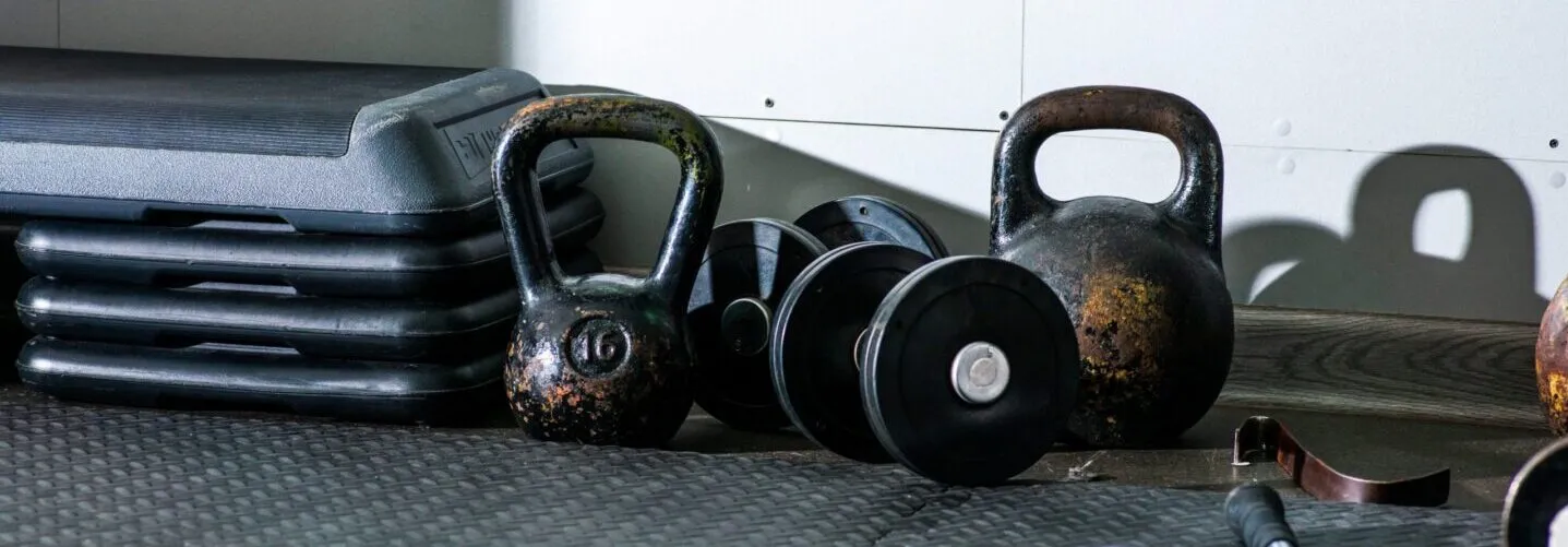 Kettlebells, dumbbells and step platforms on a rubber gym floor