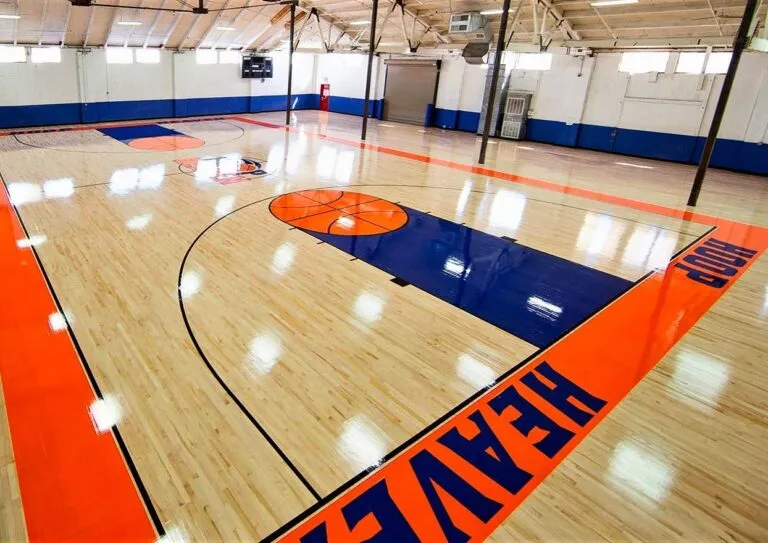Glossy maple gym floor with orange and navy painted lanes and lettering