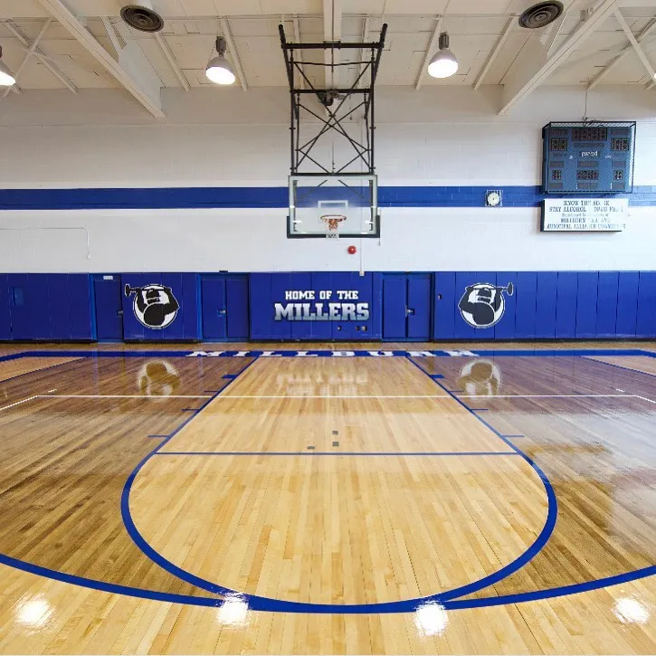 Maple gym floor with blue lines and Home of the Millers wall pads under the basket