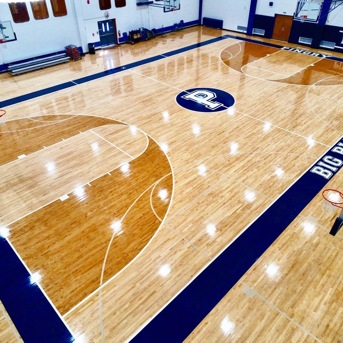 Pingry School maple gym floor with a navy painted border, stained keys and the P center-court logo