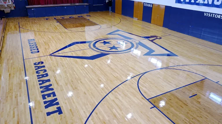 Drone view of the Blessed Sacrament Titans gym: glossy maple floor with a blue star center-court logo, BLESSED SACRAMENT sideline lettering and blue game lines