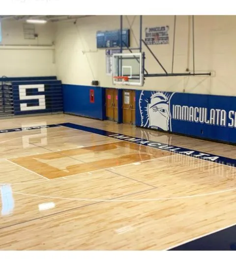 Navy Immaculata S wall pads and a navy S on the floor of a refinished maple gym