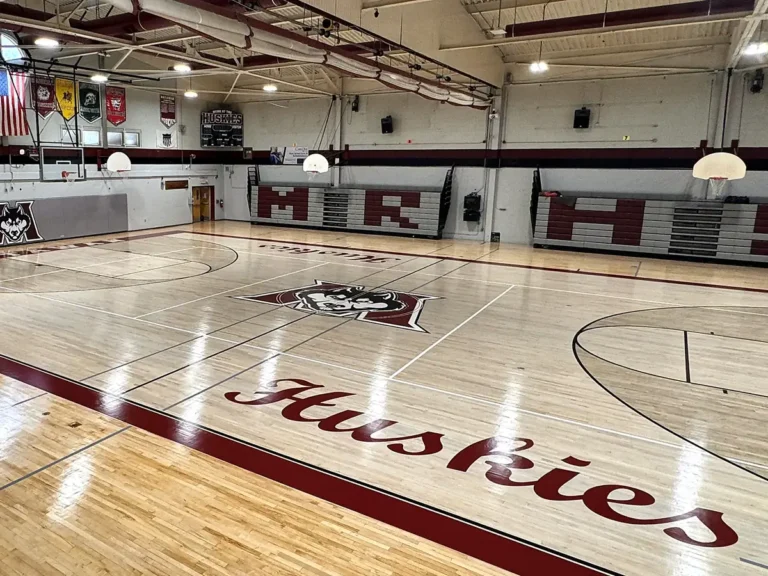 Finished maple gym floor in Matawan with painted gym floor logo, Huskies lettering and maroon border
