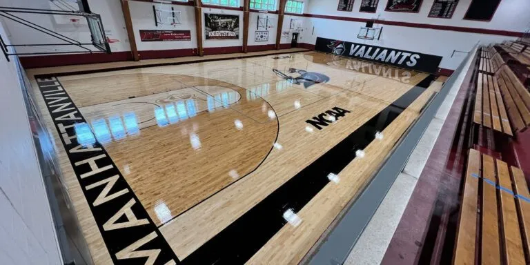 College gym maple court with black painted sidelines and MANHATTAN lettering