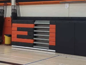 Black bleacher pads with orange school letters on a gym wall