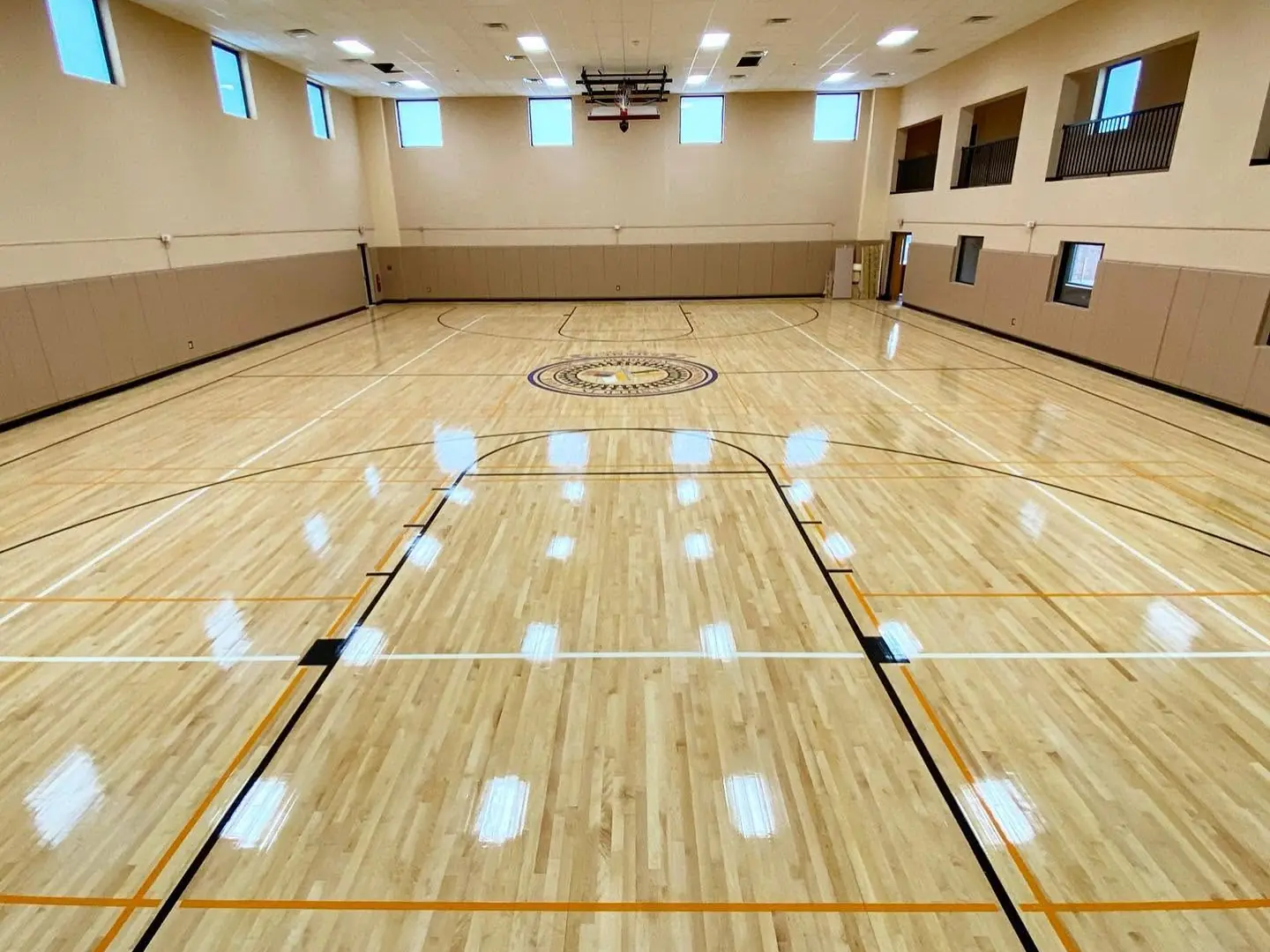 Bright, freshly finished maple gym floor seen from the baseline