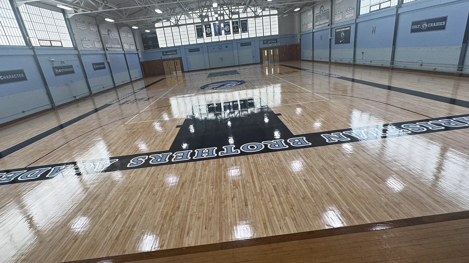 Christian Brothers Academy gym in Lincroft NJ after a sand and refinish by J and J Gym Floors: glossy maple floor with black lane and Christian Brothers Academy sideline lettering
