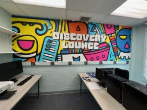 Colorful DISCOVERY LOUNGE mural graphic on a block wall in a school room