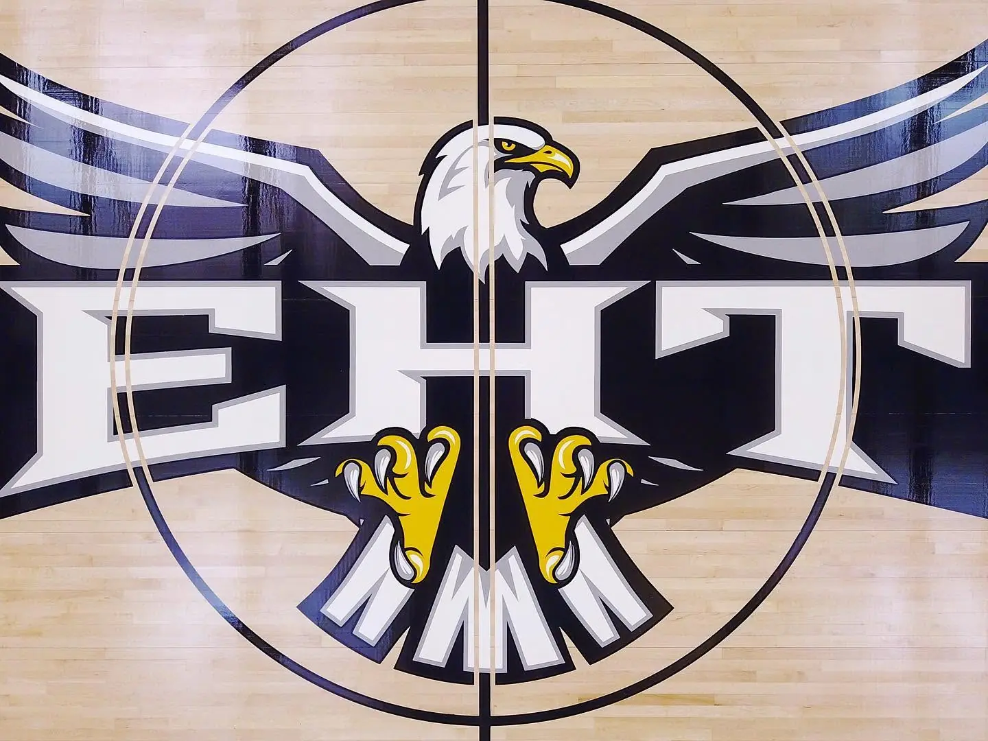 Close-up of the EHT eagle center court logo painted on a maple gym floor