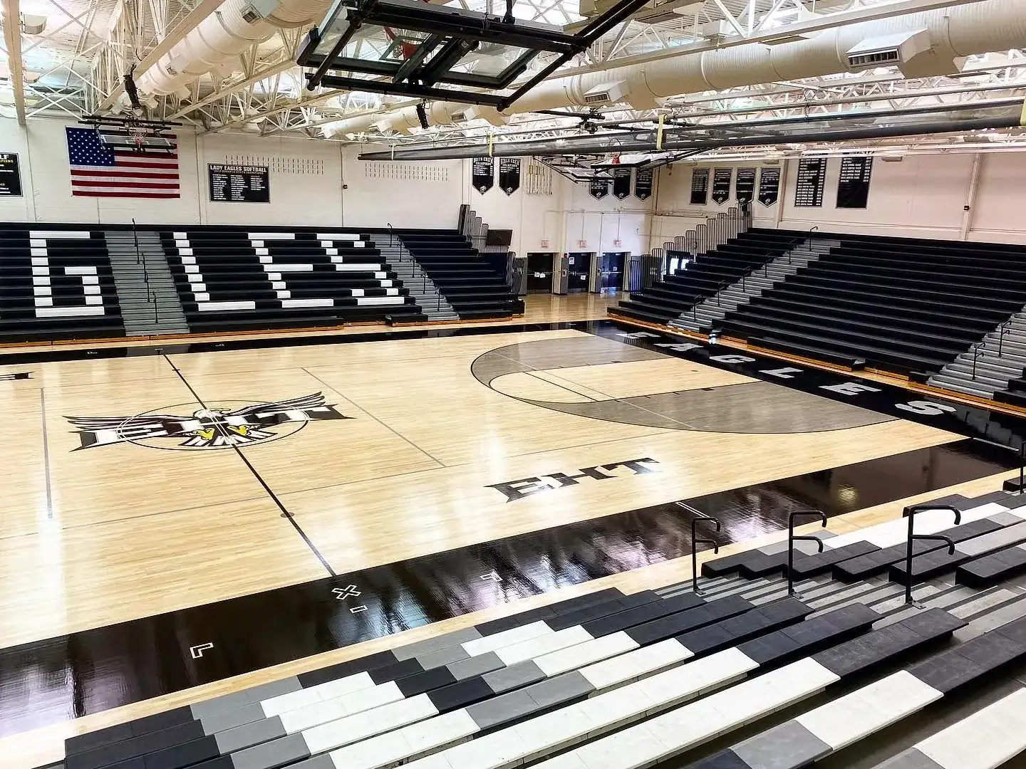 High-gloss finished maple gym floor in the EHT Eagles gym, with EAGLES lettering on the bleachers