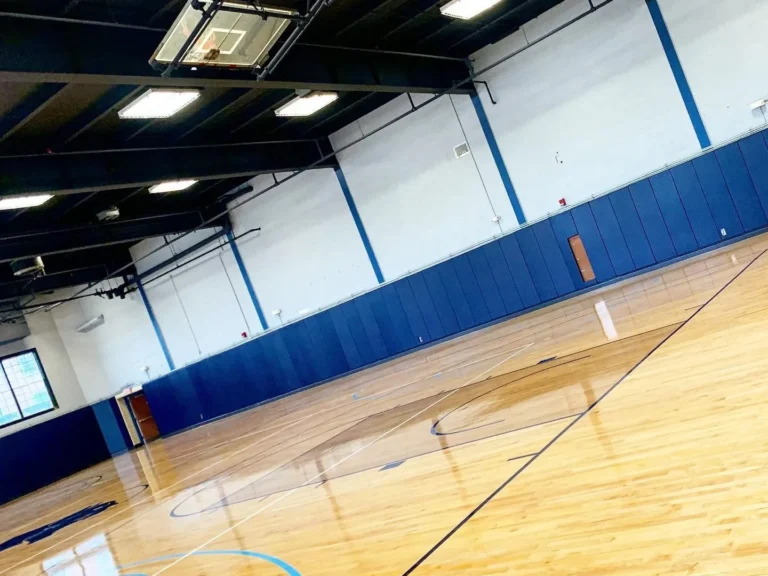 Glossy finished maple gym floor with blue wall pads and painted game lines