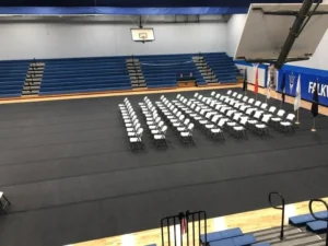 Gym floor cover rolled out over a gym floor with rows of chairs for an event