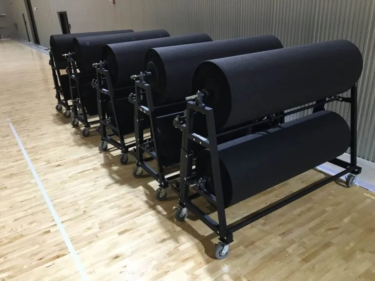 Gym floor cover rolls stored on rolling racks