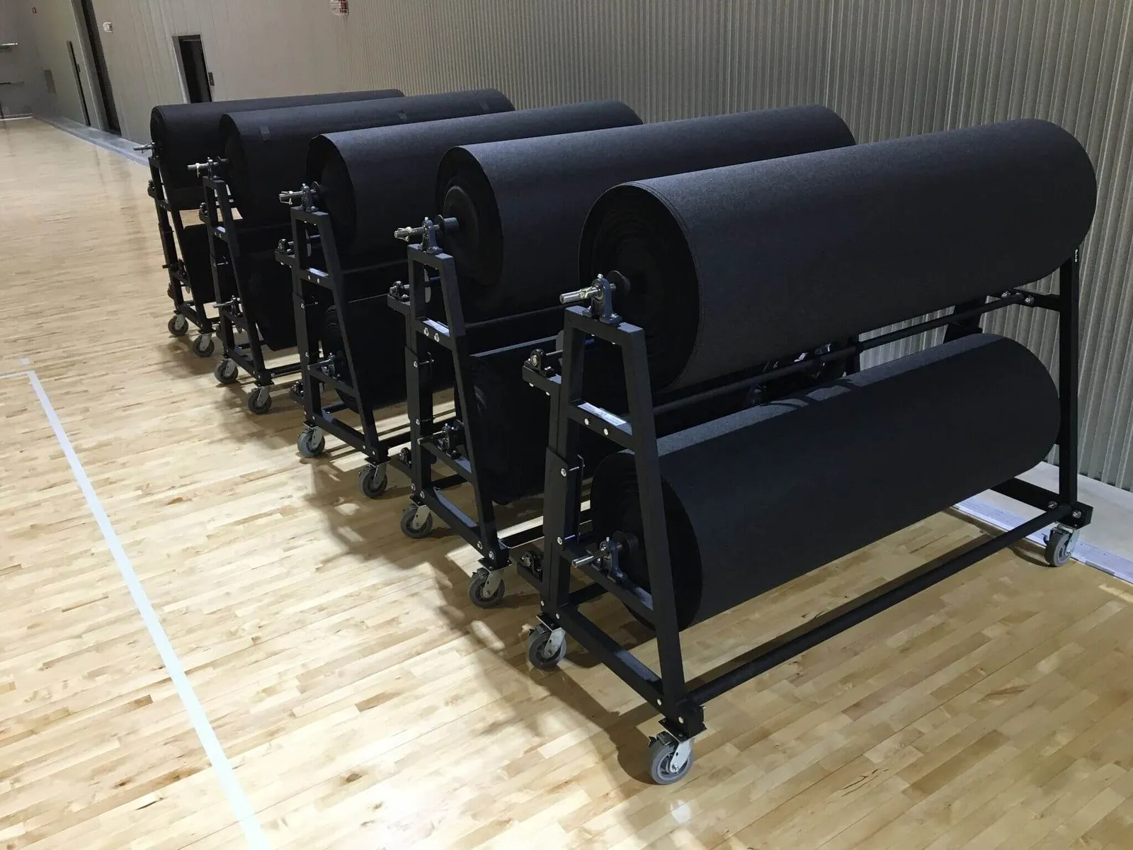 Gym floor cover rolls stored on rolling racks