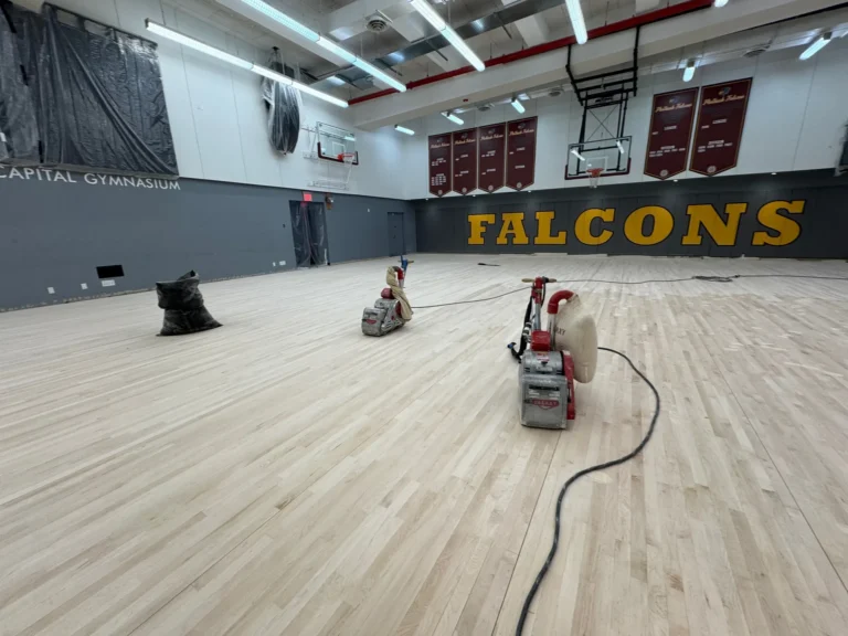 Floor sanding machines partway through sanding a maple gym floor