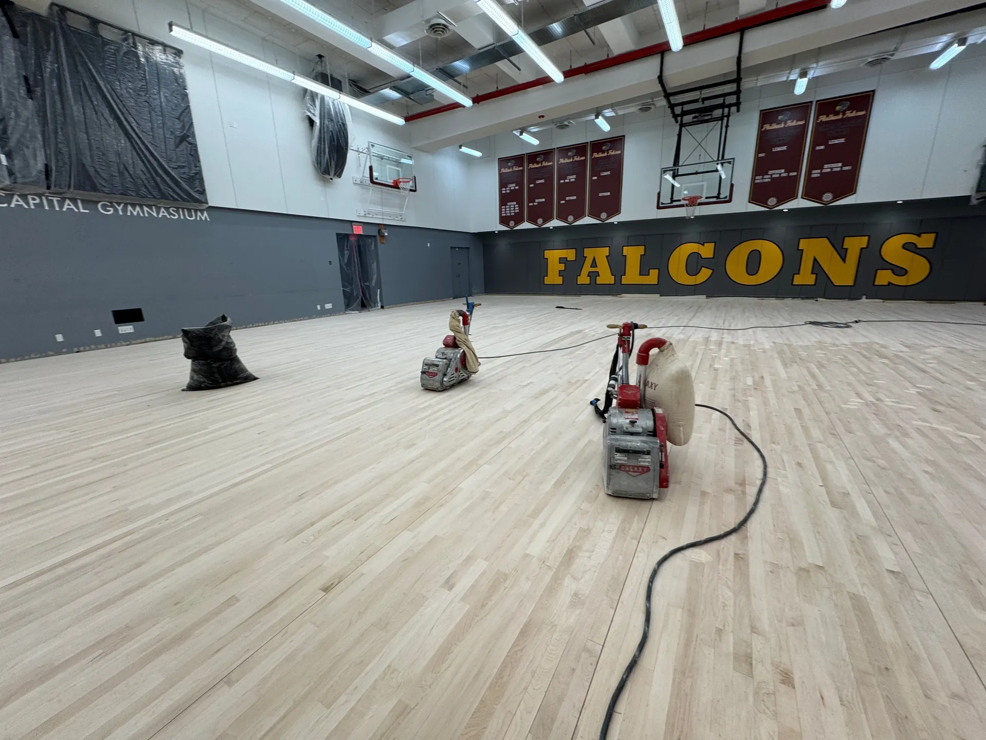 Floor sanding machines partway through sanding a maple gym floor