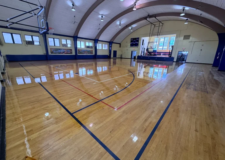 High-gloss maple gym floor in an arched-roof gym with navy game lines