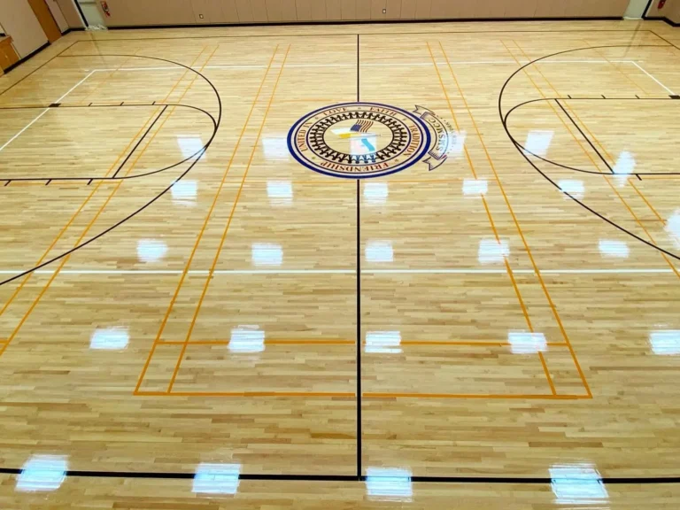 Glossy finished maple gym floor with a center seal and orange and black game lines