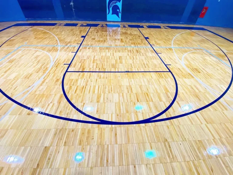Freshly finished high-gloss maple gym floor with navy game lines