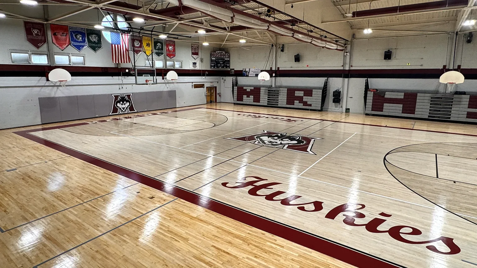 Huskies gym after J and J Gym Floors refinished the maple floor, with maroon border, painted husky center logo and Huskies lettering