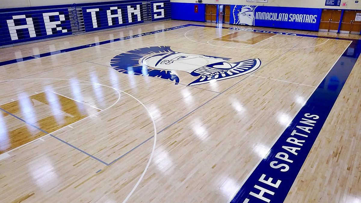 Immaculata Spartans center-court logo and blue painted sidelines on a maple gym floor