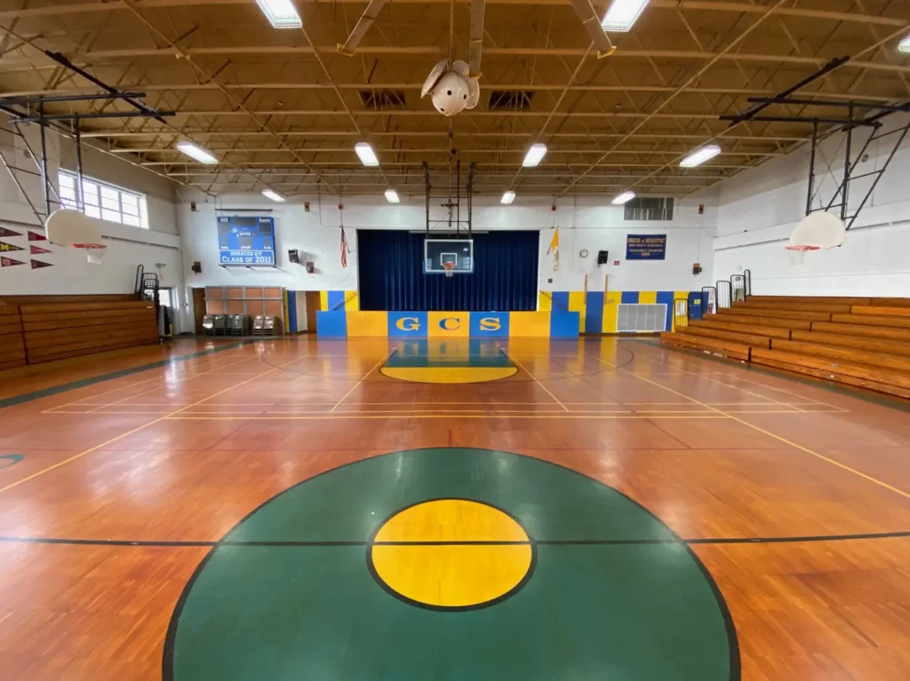 Greenwich Catholic School gym floor before: worn orange-toned finish and old lines