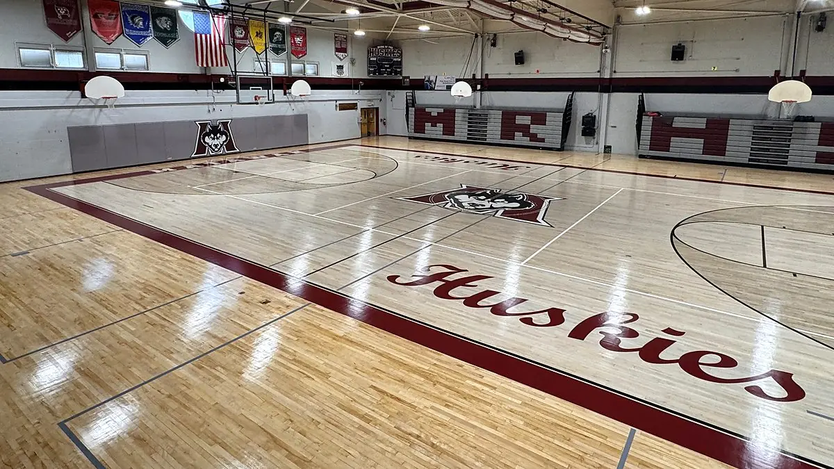 Freshly refinished maple gym floor with painted Huskies logo and game lines by J and J Gym Floors