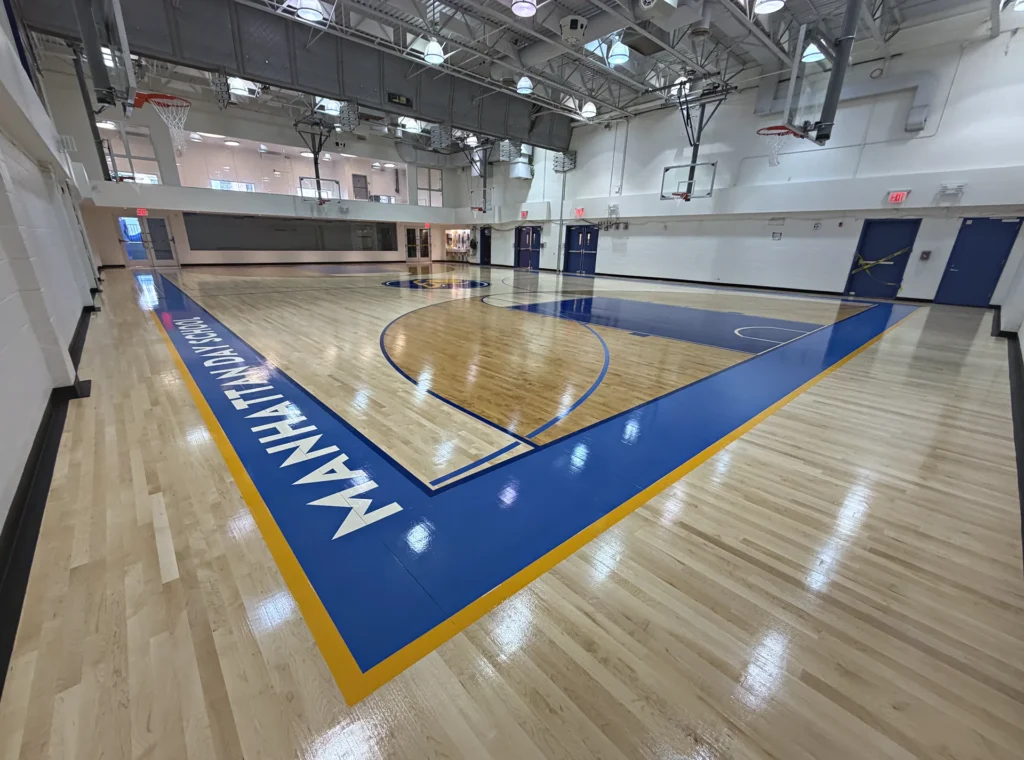 New maple gym floor at Manhattan Day School in New York City installed by J and J Gym Floors, with royal blue and gold border and school name lettering