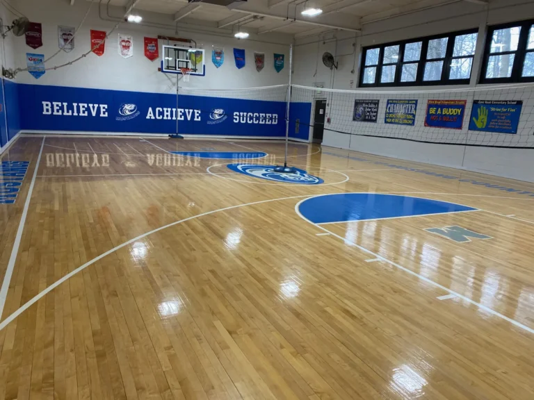 Bright maple gym floor with blue painted keys and a glossy finish