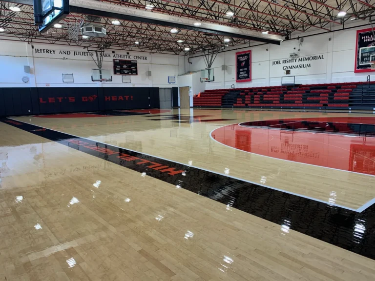 High-gloss maple gym floor with a red center circle and black and white painted lane