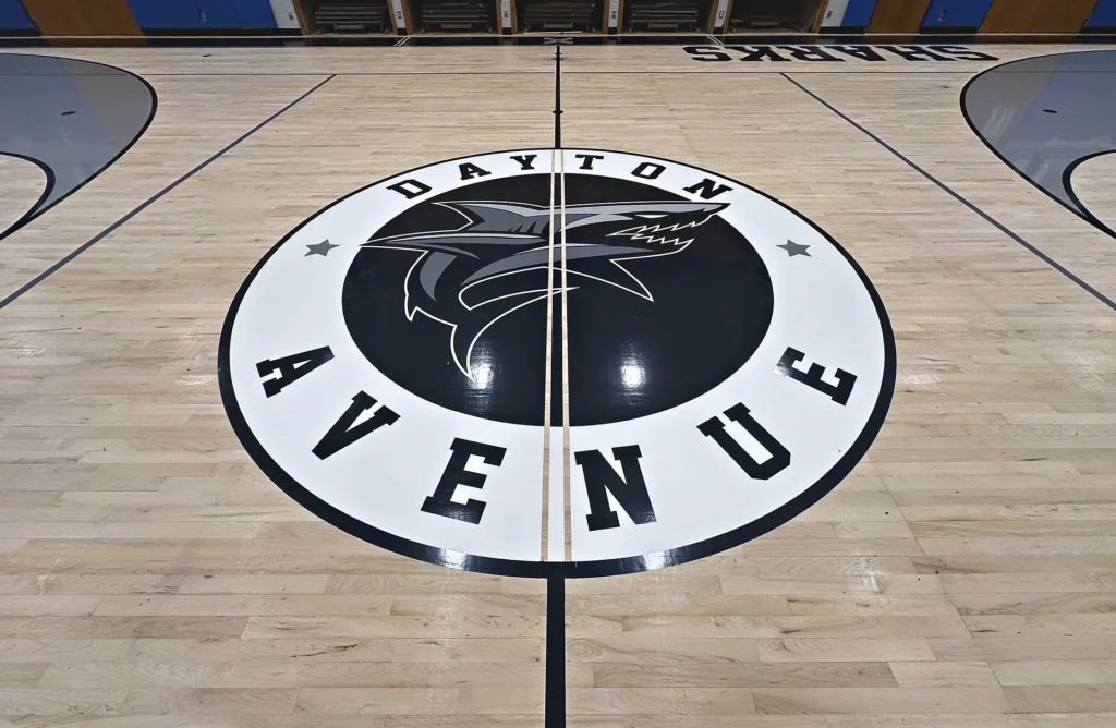 Dayton Avenue School Sharks black and white center-court logo painted on a light maple gym floor in Manorville, NY
