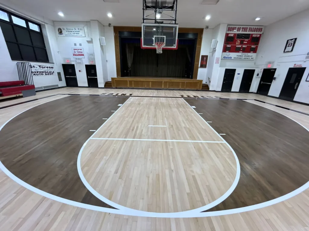 New maple gym floor with a dark stained perimeter, white game lines and a glossy finish
