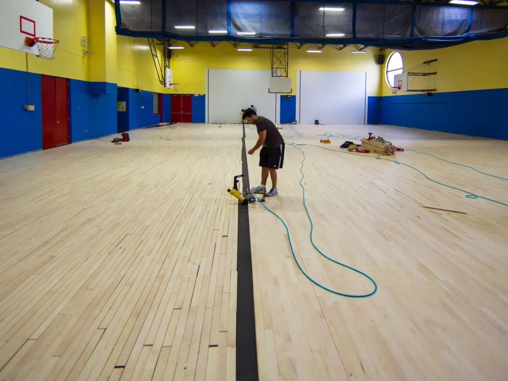 J and J installer working on a newly laid maple gym floor before sanding and finish