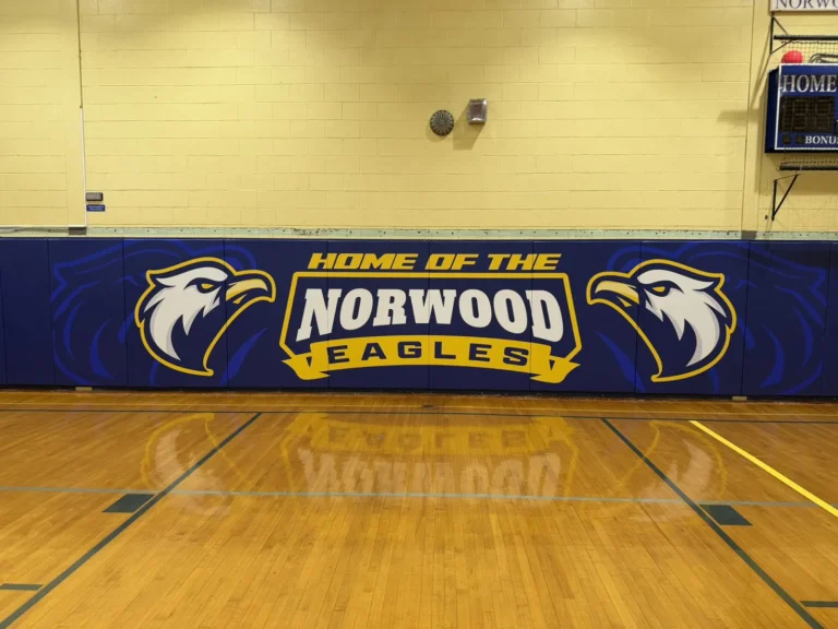 Custom navy gym wall pads with Norwood Eagles logo installed by J and J Gym Floors
