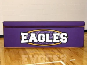 Purple padded scorer's table printed with the Eagles logo on a maple gym floor