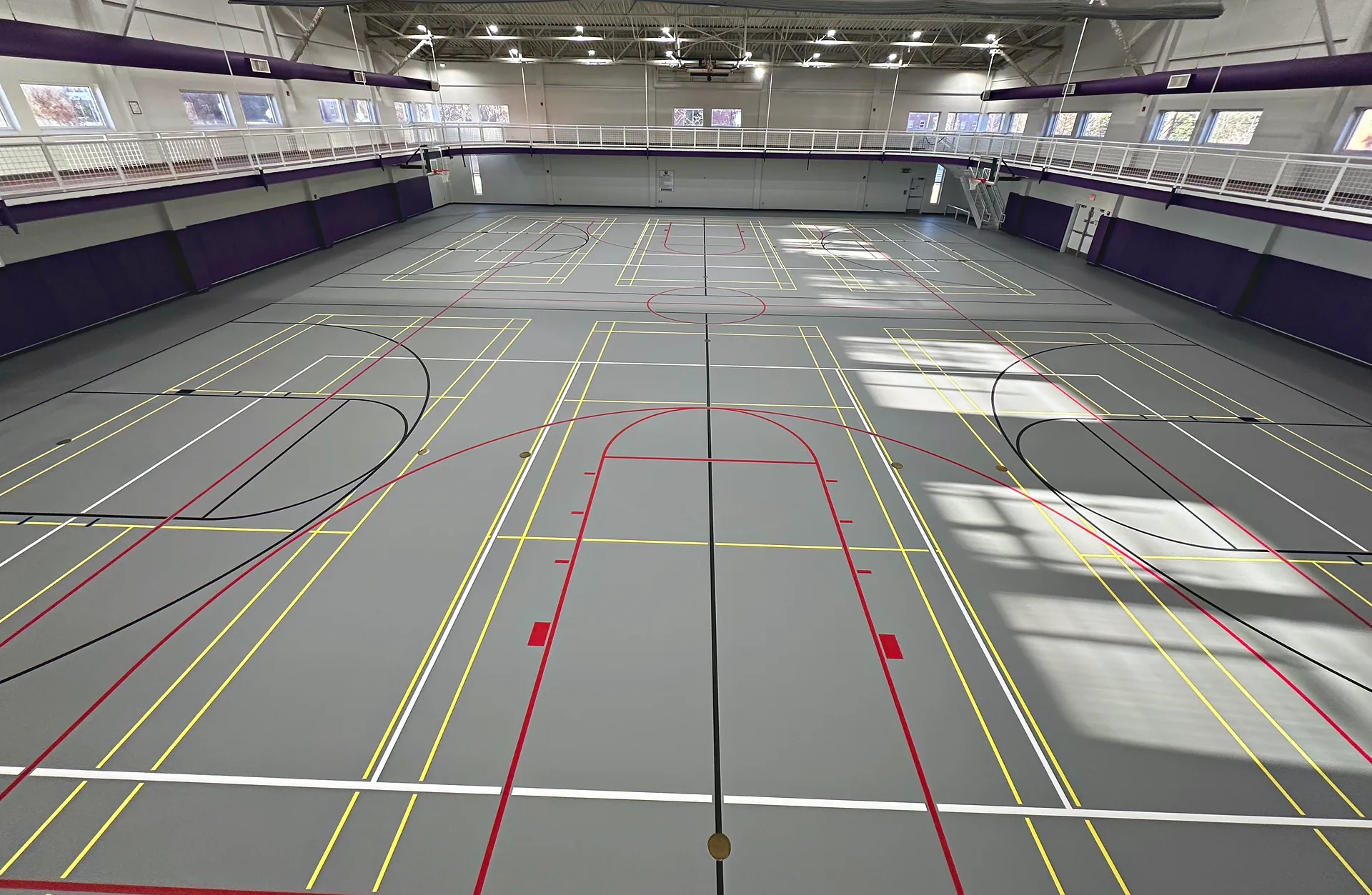 Gray poured multi-sport gym floor in Georgia with multi-color game lines for basketball, volleyball and more, seen from above
