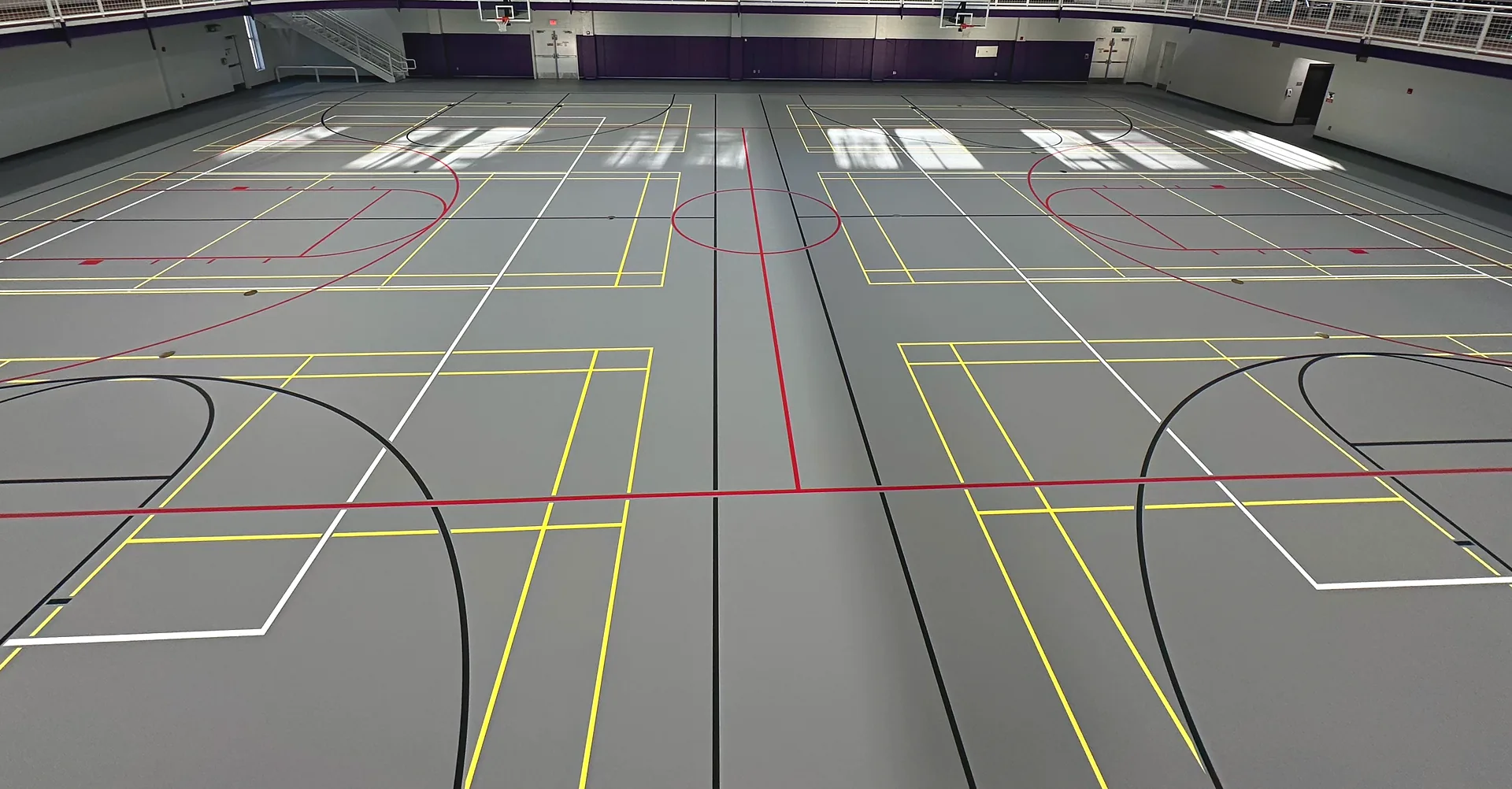Wide view of a gray multi-court poured gym floor in Georgia with yellow, red, white and black game lines