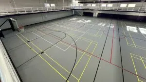 Gray poured rubber multi-sport gym floor with yellow, red, black and white game lines