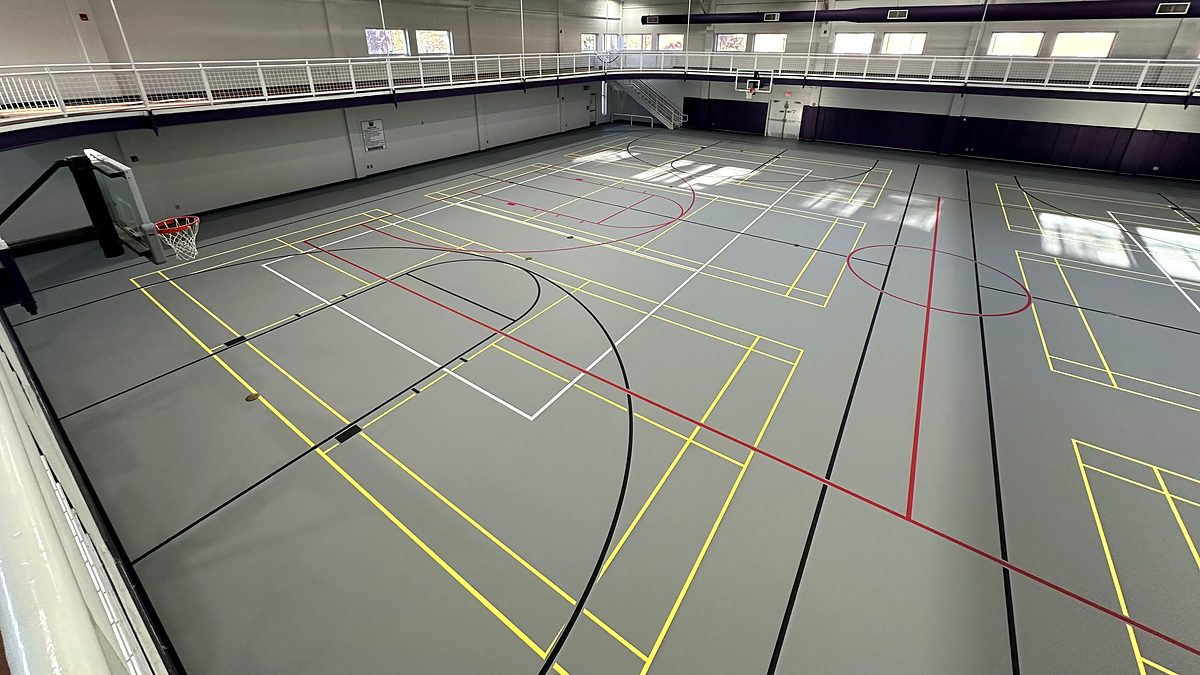 Gray poured rubber multi-sport gym floor with yellow, red, black and white game lines