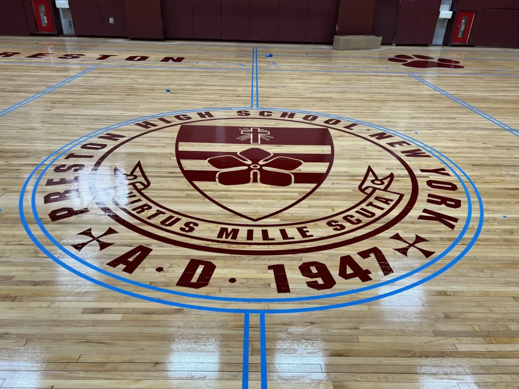 Preston High School seal painted in the center circle of a maple gym floor with blue game lines