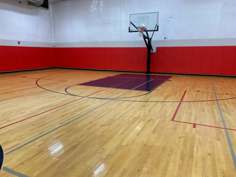 Red gym wall pads wrapping a gym with a clean, finished maple floor