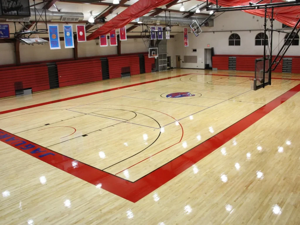 High-gloss refinished maple gym floor with a red painted lane, red border and crisp game lines