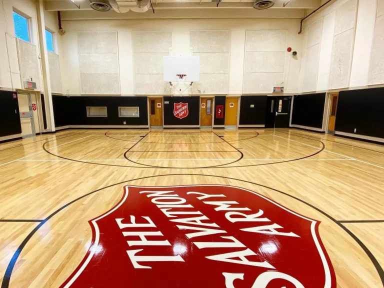 Red Salvation Army shield center court logo on a maple gym floor
