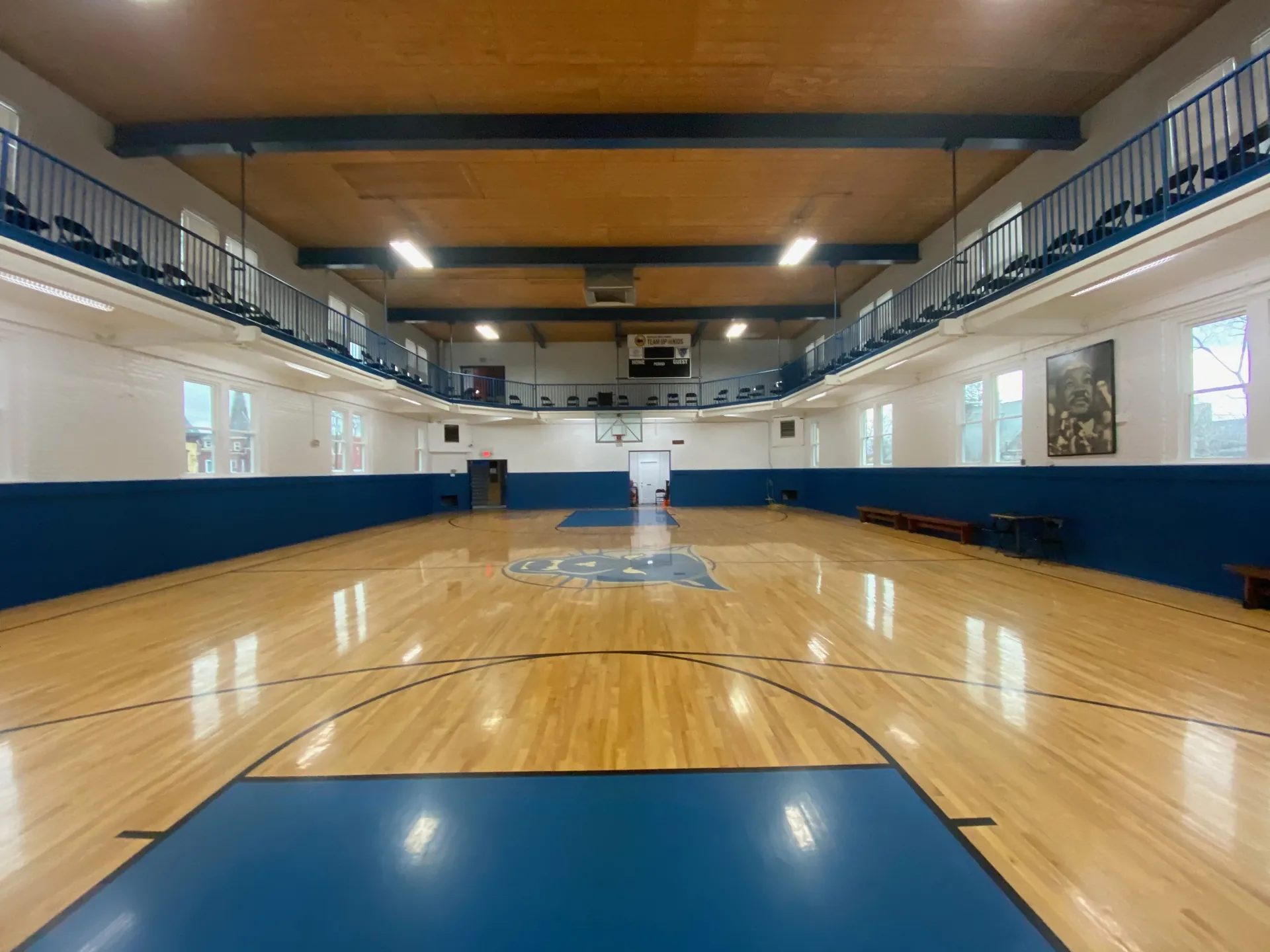 Two-level gym with a balcony, warm maple floor and blue painted areas