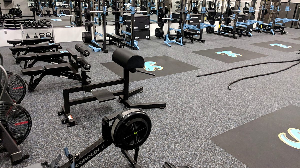 Weight room with rubber floor, power racks and floor logos